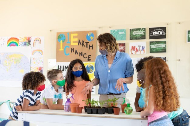 female-teacher-wearing-face-mask-showing-plant-pots-students