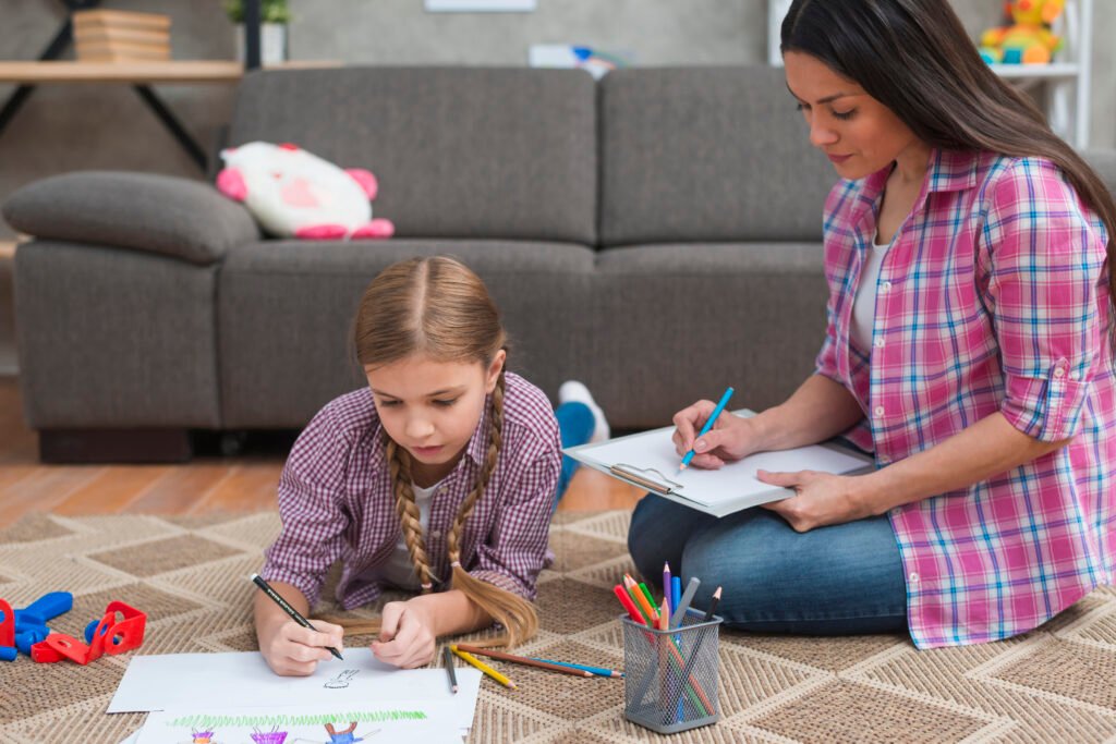 young-female-psychologist-taking-notes-while-girl-drawing-white-paper